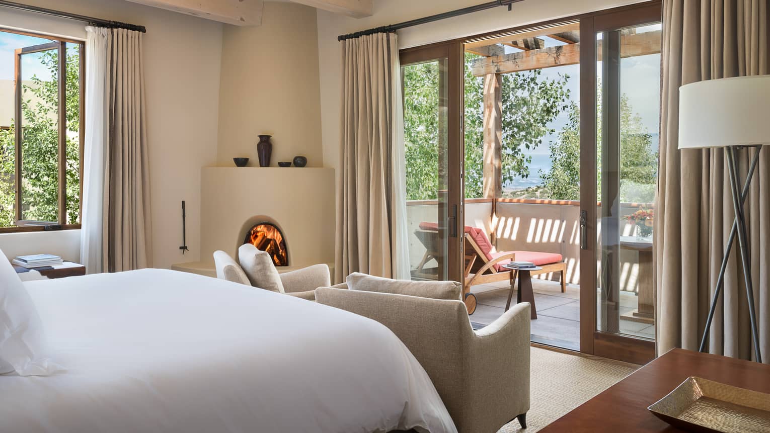 Mountain-View Casita bed, curved white fireplace, chairs by balcony doors