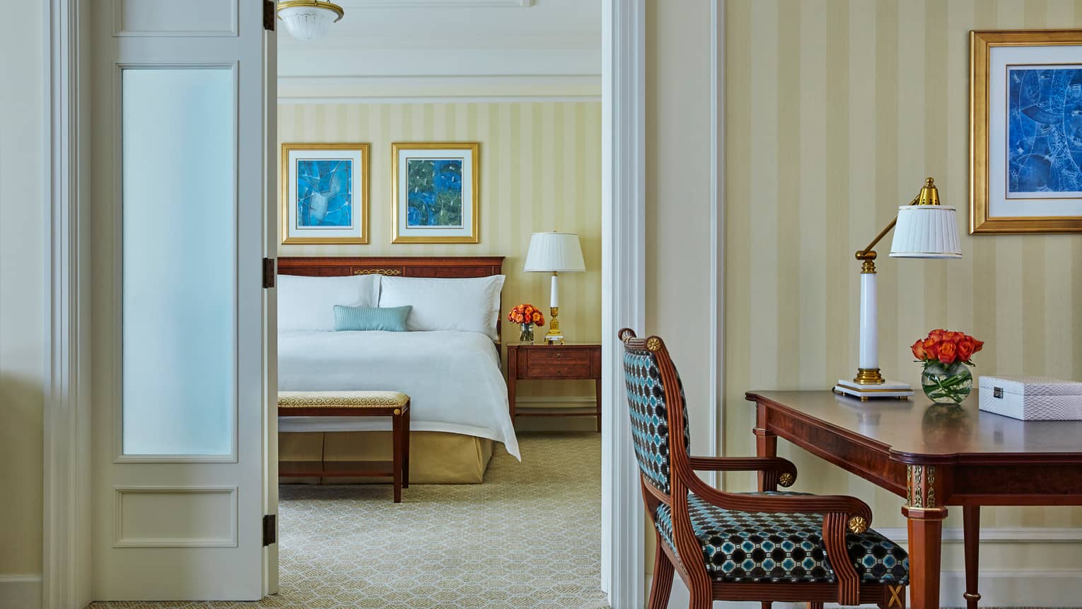 Hotel room desk, chair, open door to bedroom