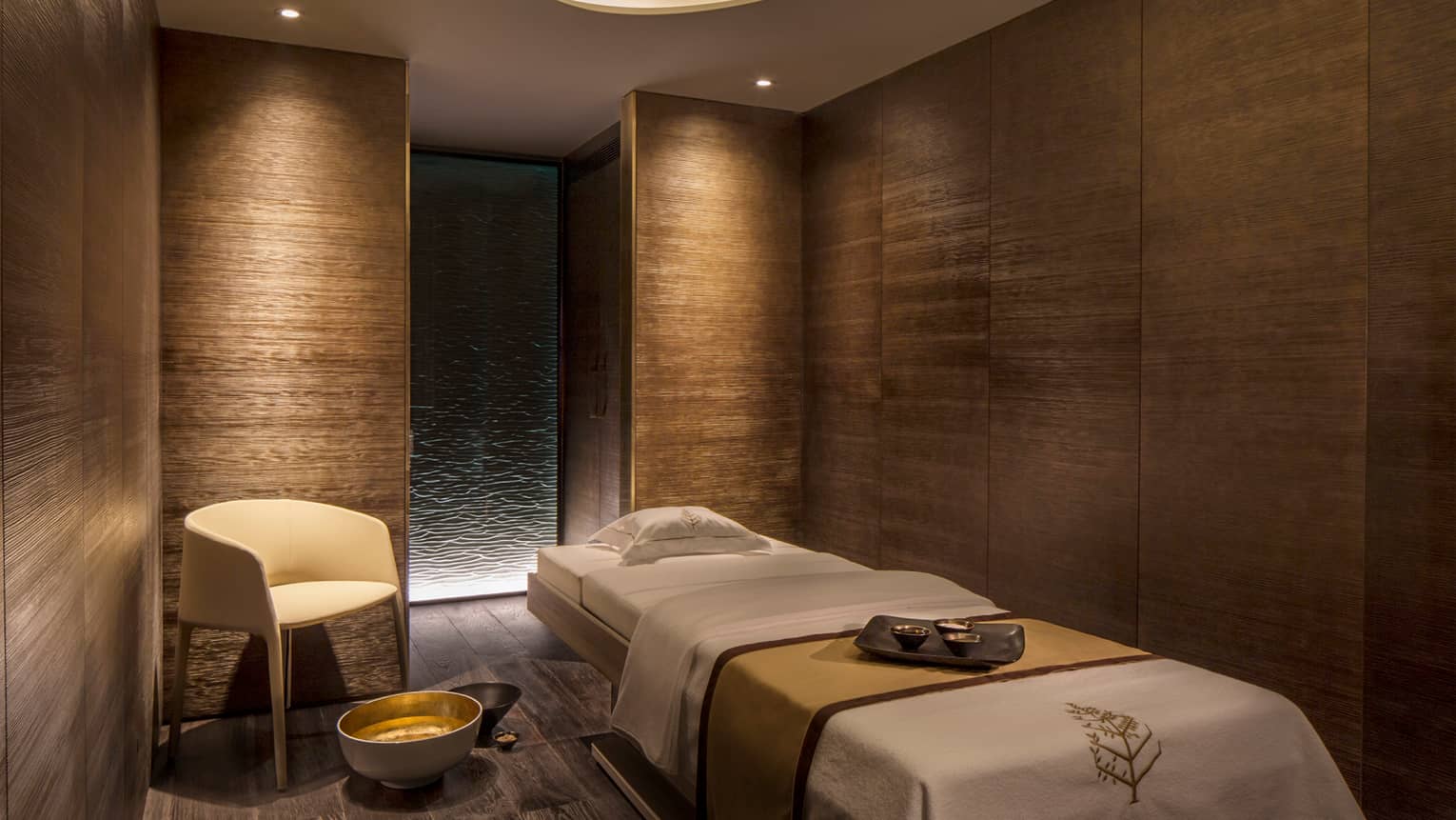 View of private massage room in spa and wellness centre, wood grain walls and low lighting