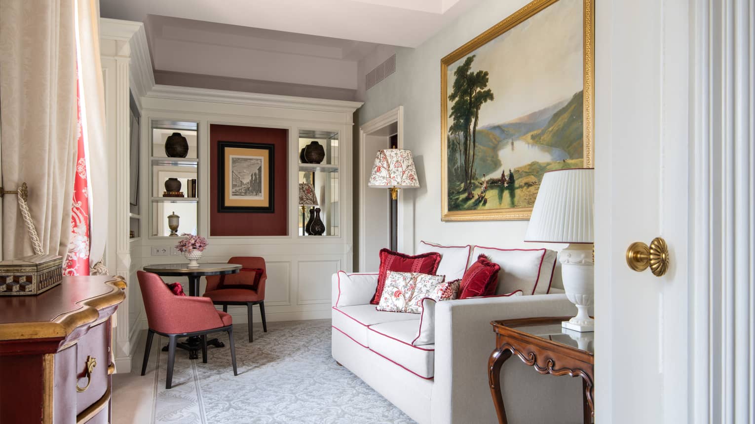 Four Seasons Room sitting room with sofa, small table and two chairs, framed artwork and built-in shelving at Four Seasons Hotel Florence