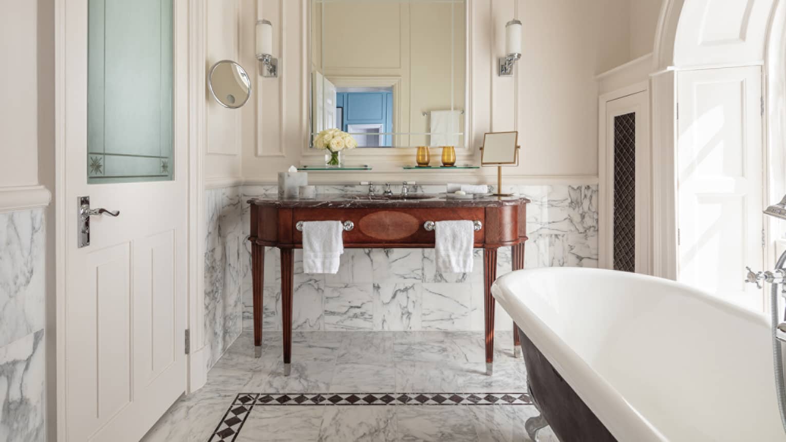 Bathroom with marble accents, large soaking tub, double wooden vanity, mirror