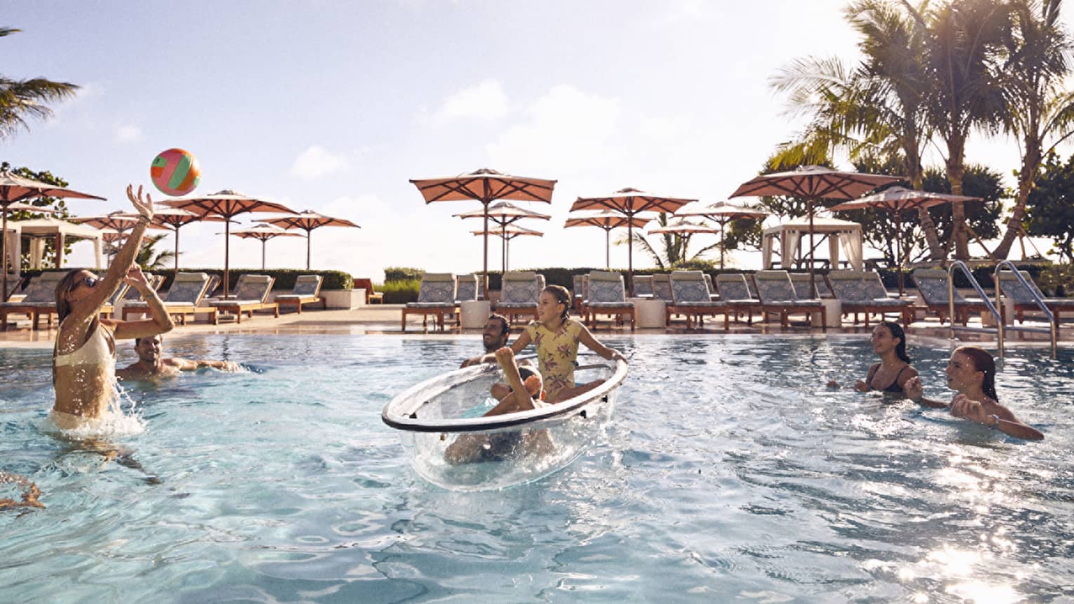Guests throwing a beach ball in the pool and laying on a float
