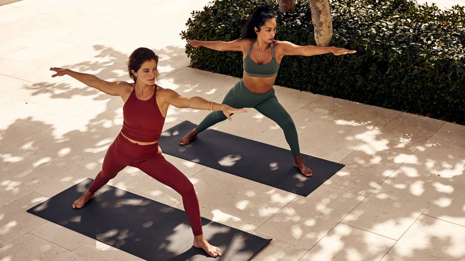 Two women doing yoga outside.