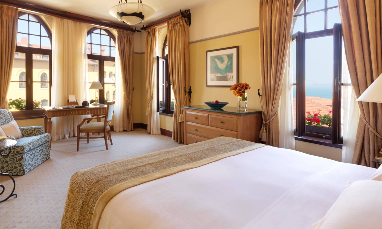 Deluxe Room bed with armchair, desk in front of corner windows