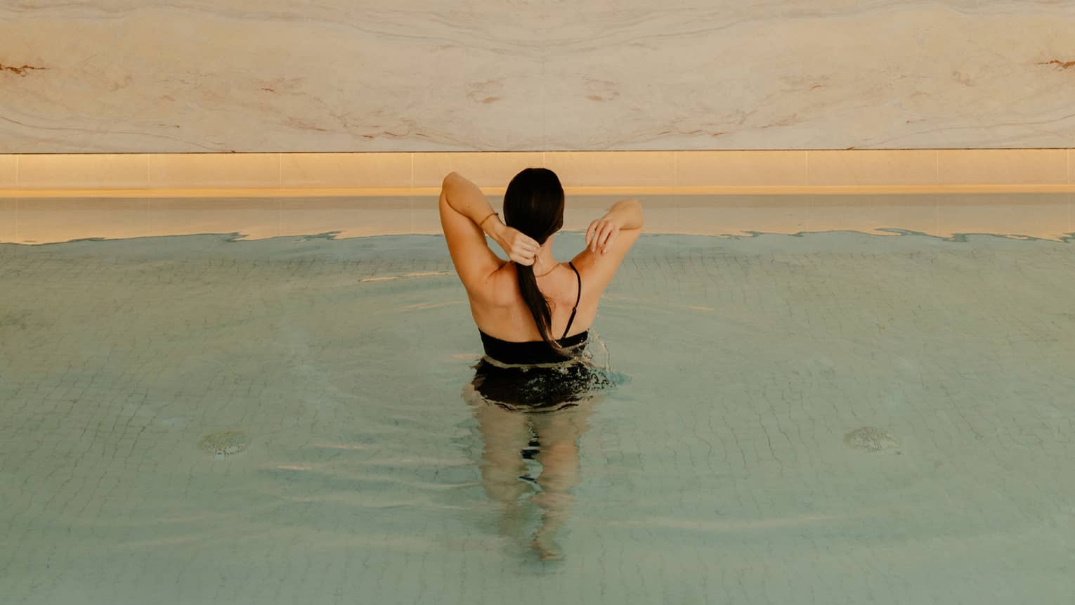 Person wearing a swimsuit and standing in the pool water.