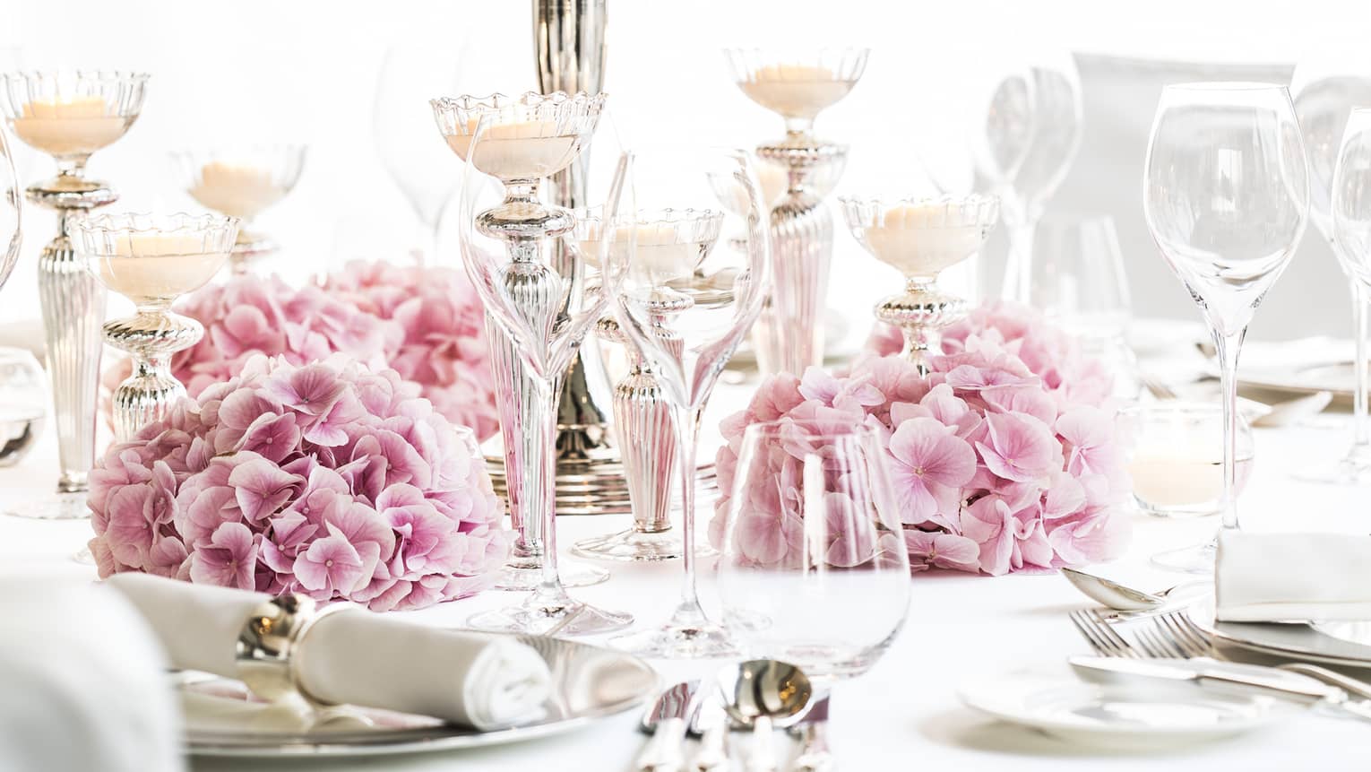 Bright banquet dining table with pink flowers, tall candelabra with roses