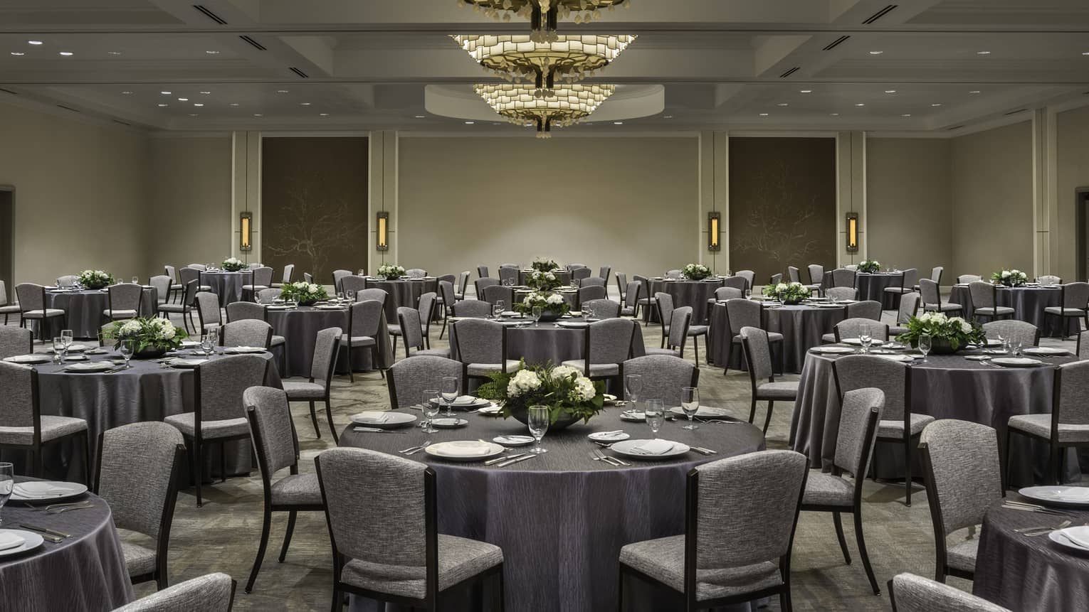 Round banquet tables with grey linens, chairs in ballroom