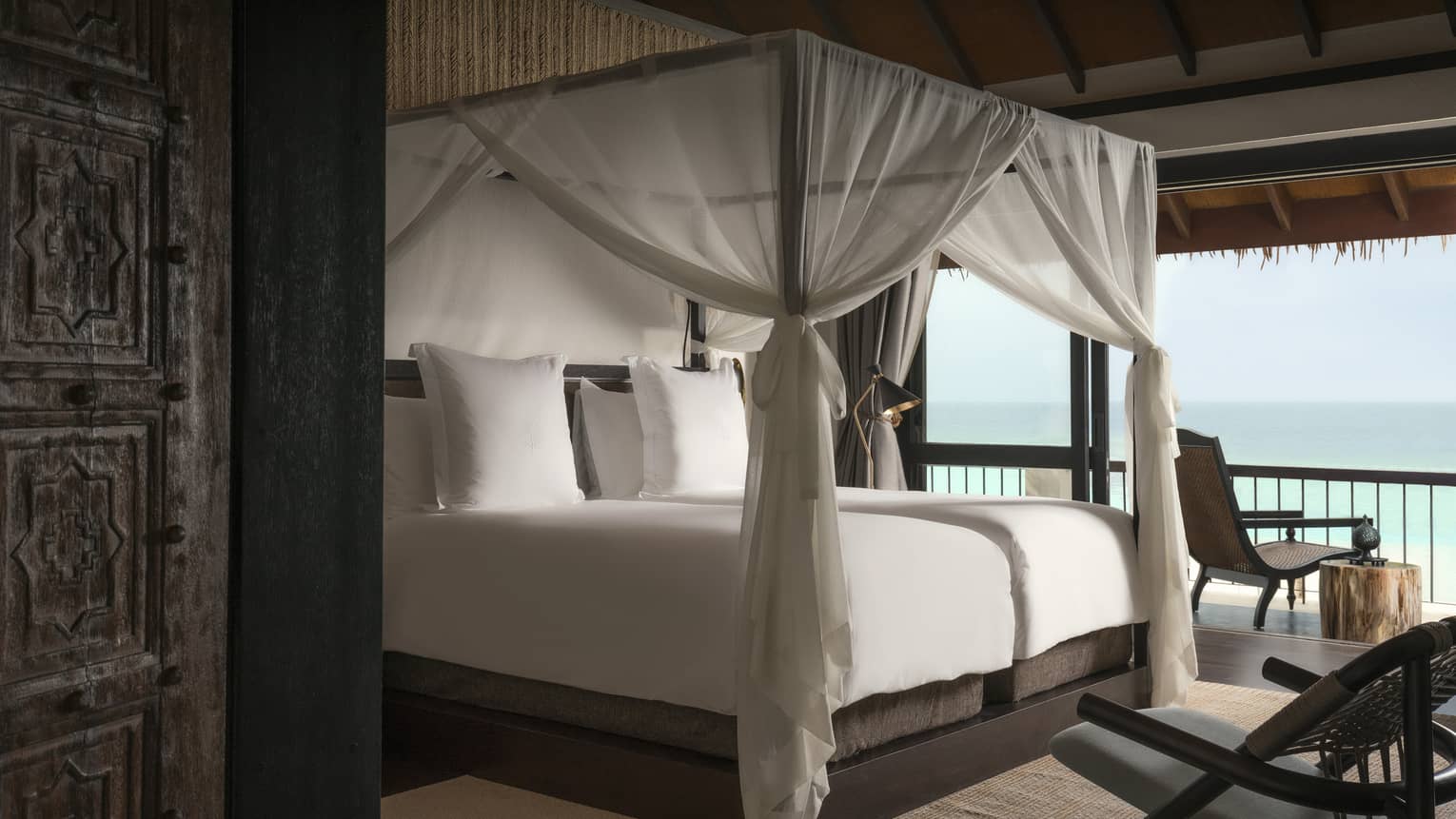 Villa poster bed with white canopy by open wall with ocean views
