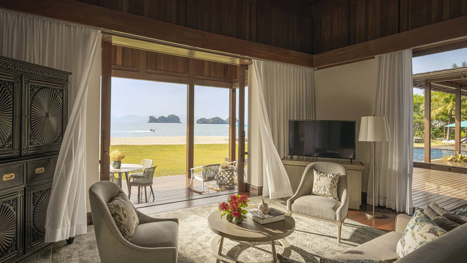 Sitting room with sofa and two chairs, with walk-out wooden terrace and beach view