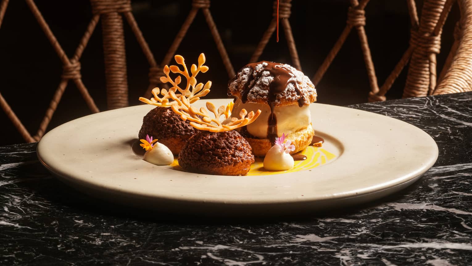 Profiteroles with chocolate sauce on a white plate