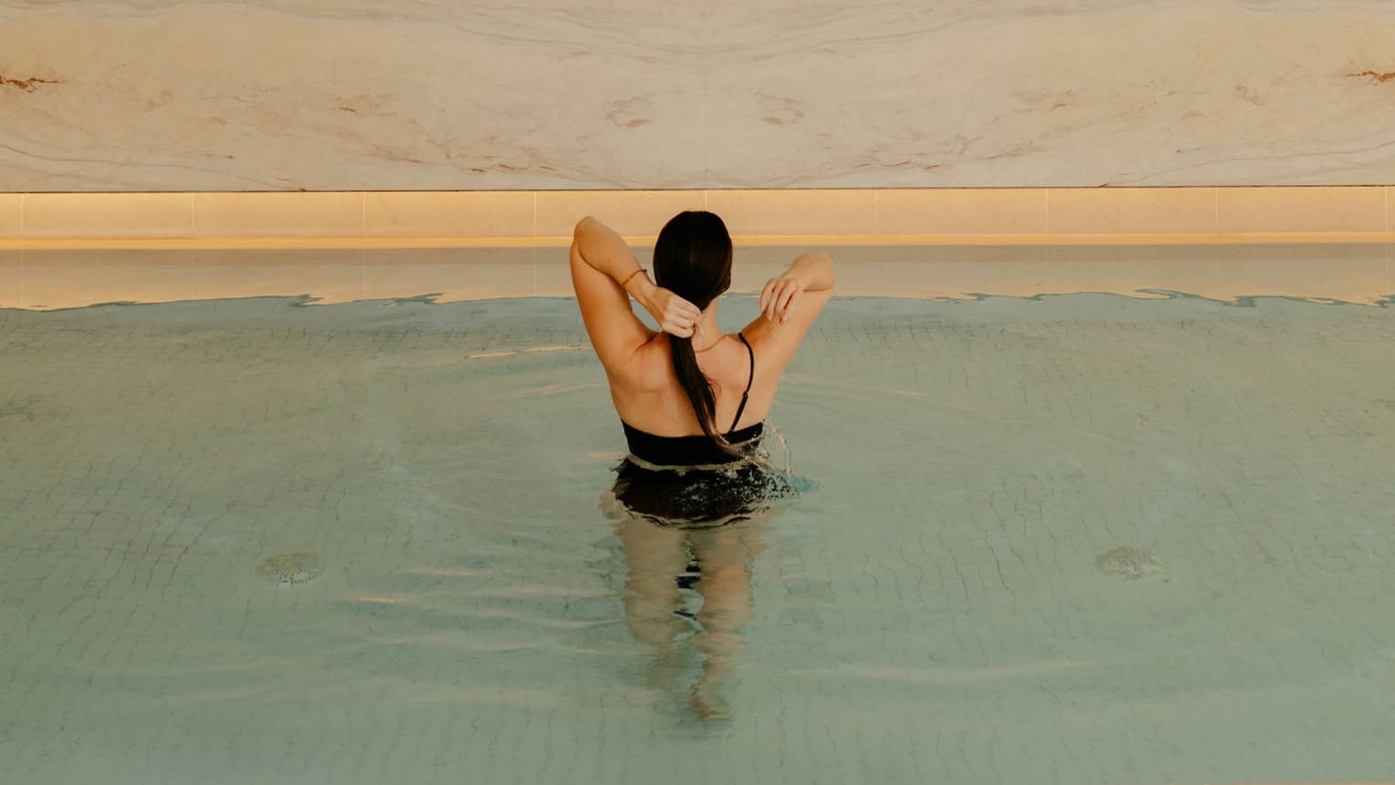 Person wearing a swimsuit and standing in the pool water.