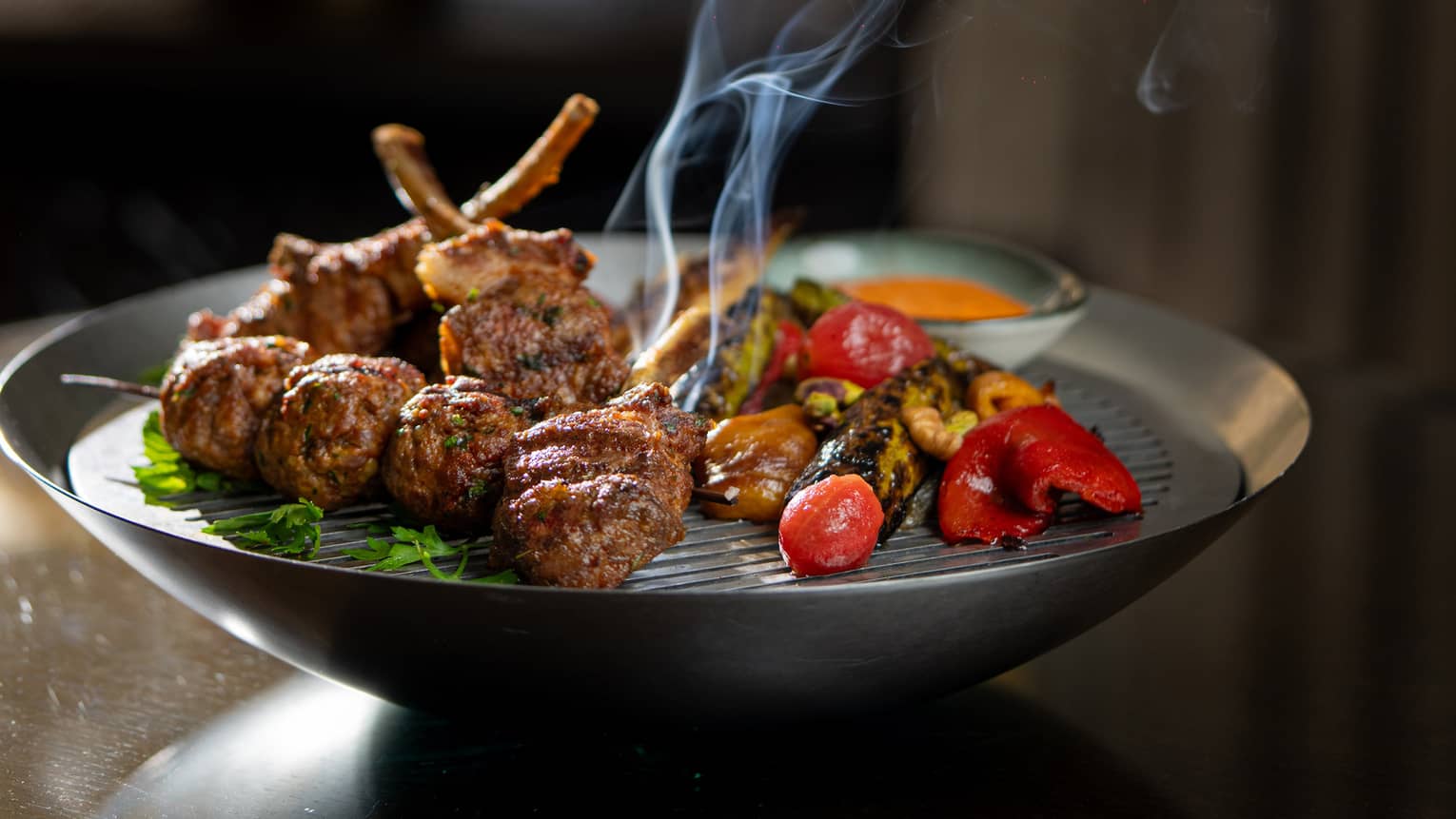 Steaming mixed grilled meat with red pepper on metal plate