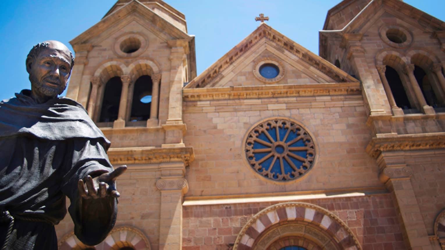 Statue of monk in front of stone New Mexico cathedral church