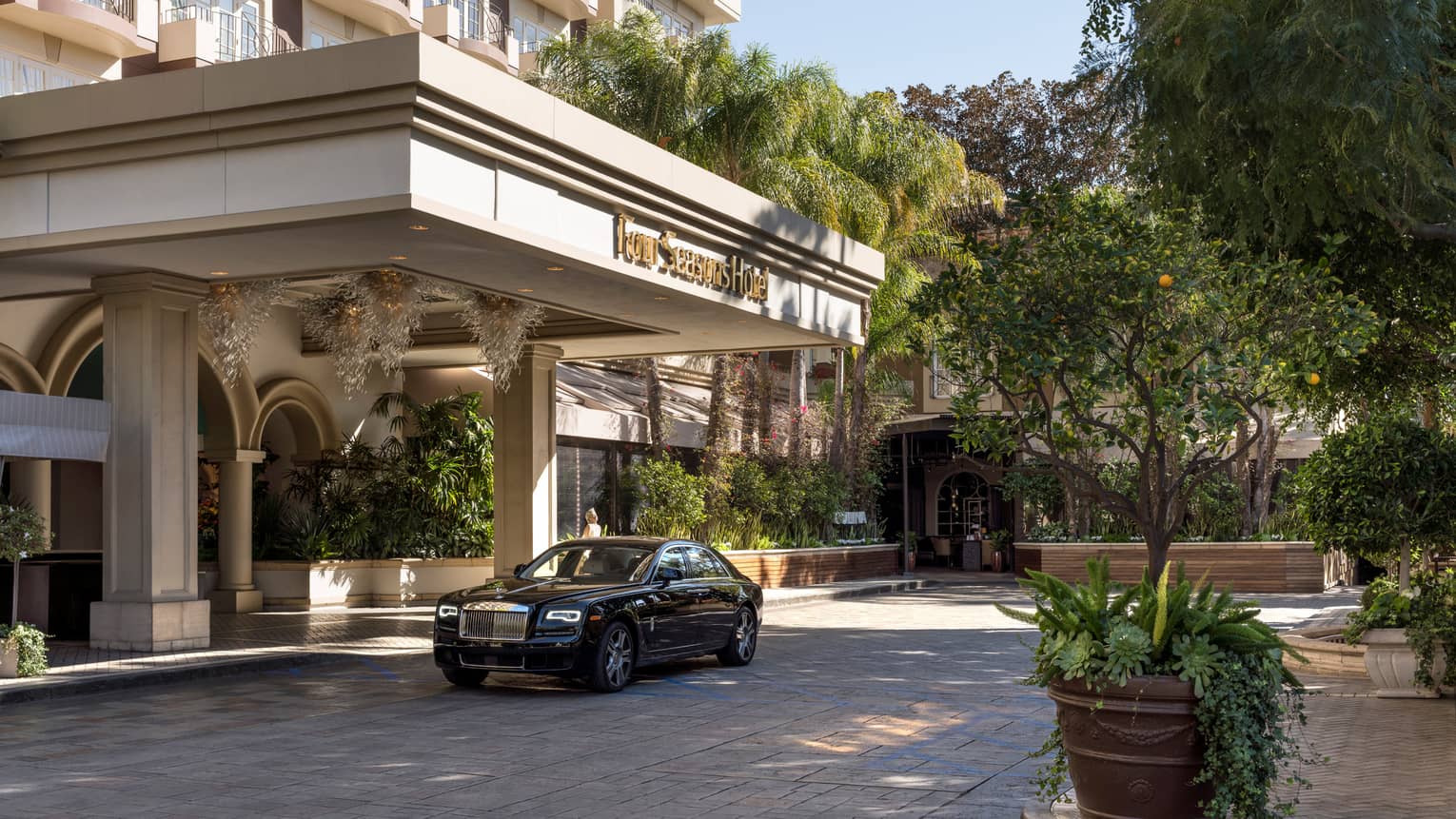 The exterior of a hotel with a car parked outside of its entrance on a driveway.