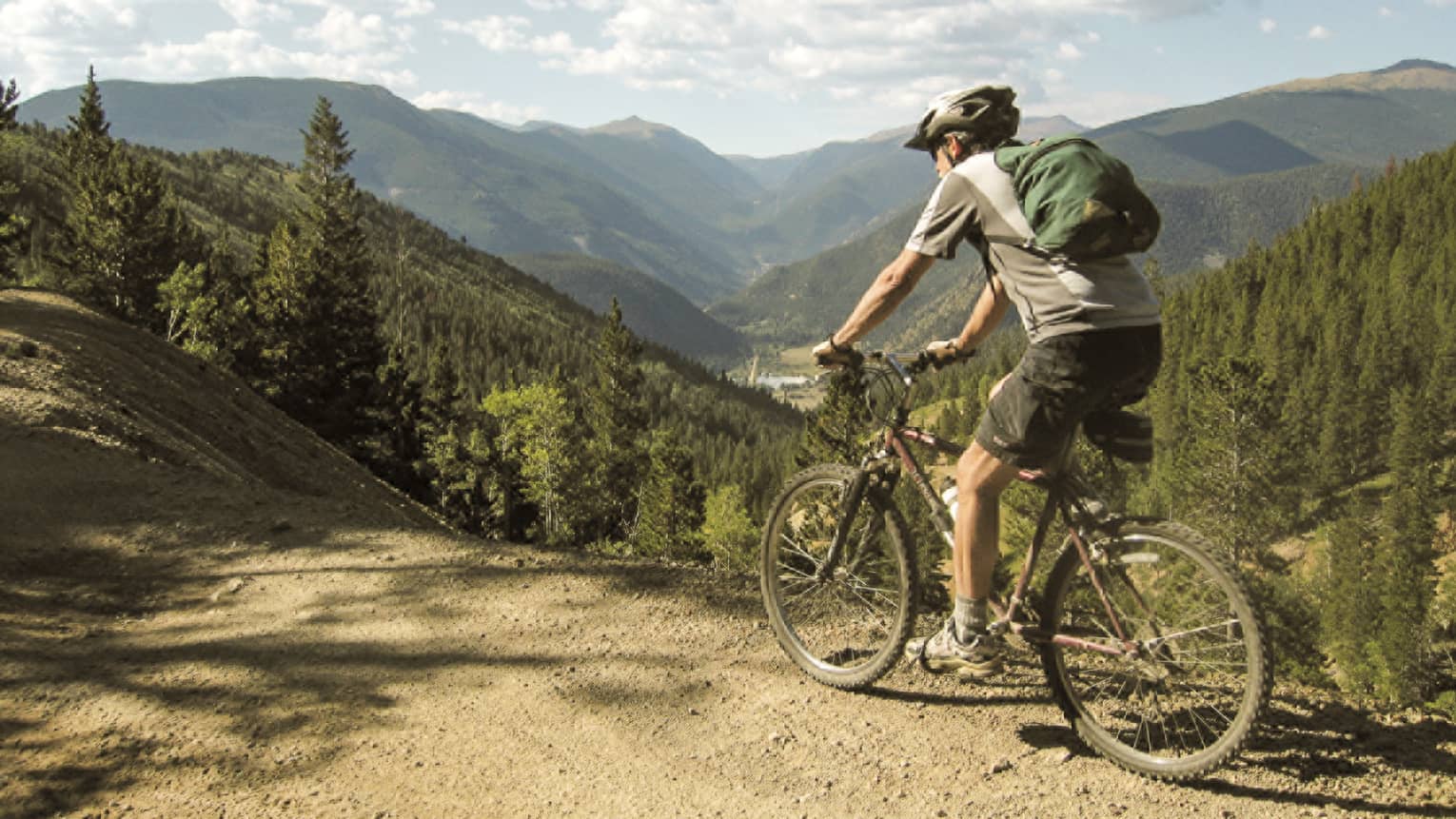 Man in shorts, Tshirt, helmet on bicycle on summer mountain bike trail