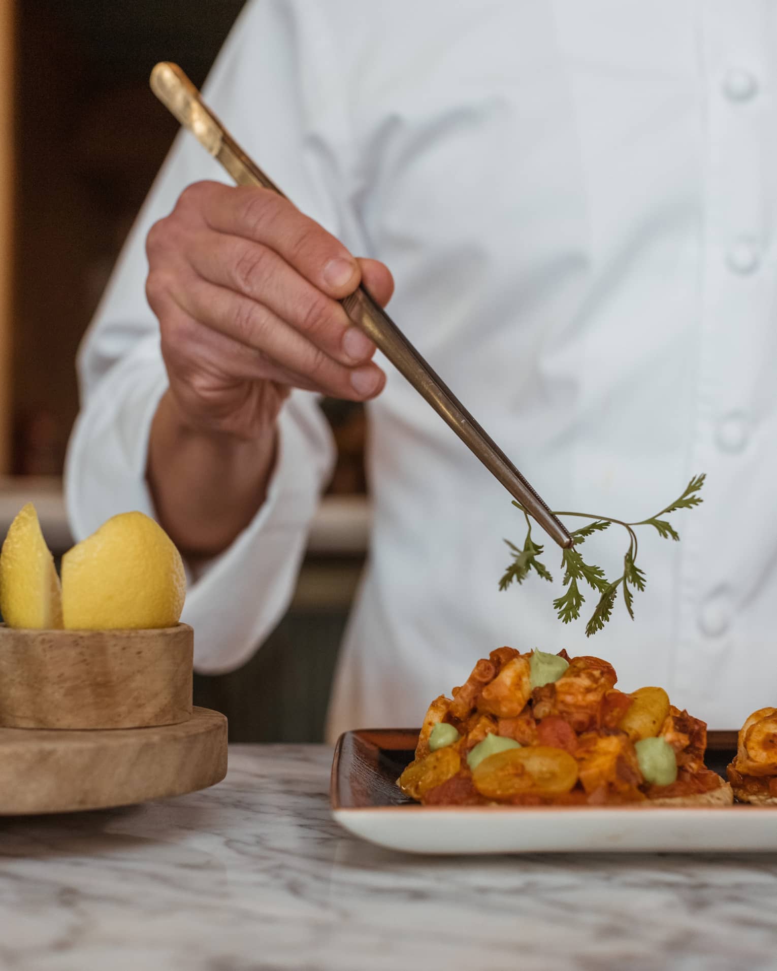 A chef picking up an herb with a utensil.