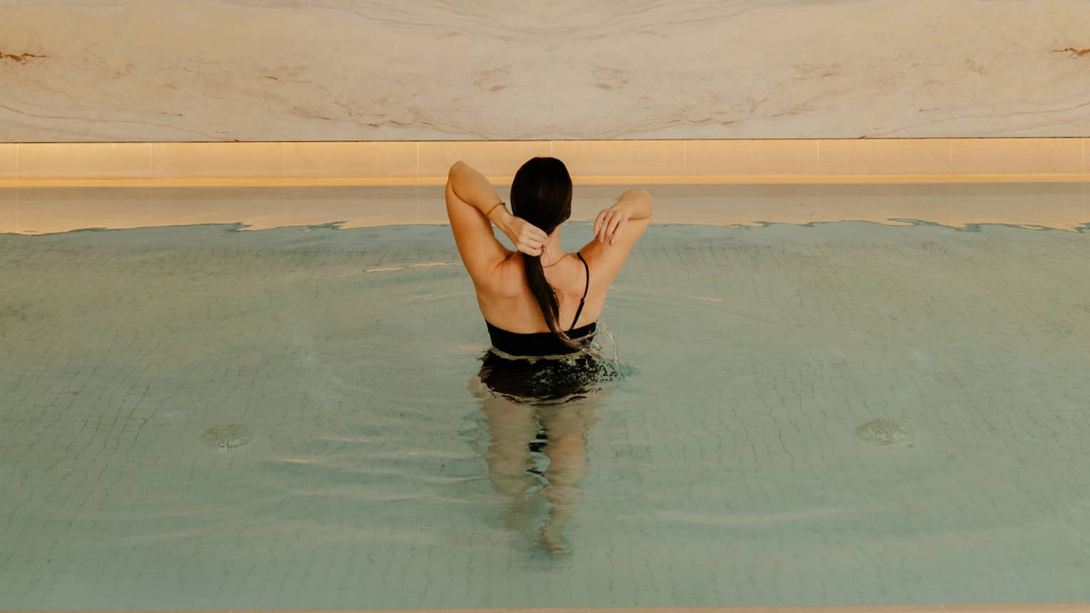 Person wearing a swimsuit and standing in the pool water.