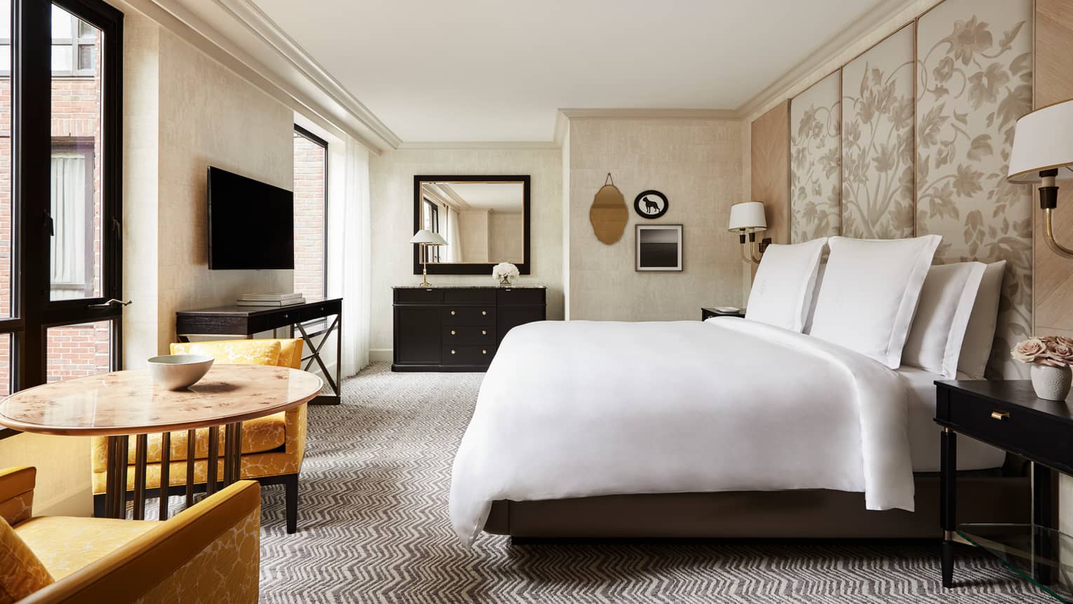 Courtyard-View Room bed, tall fabric floral headboard, black vanity, round dining table, yellow fabric chairs