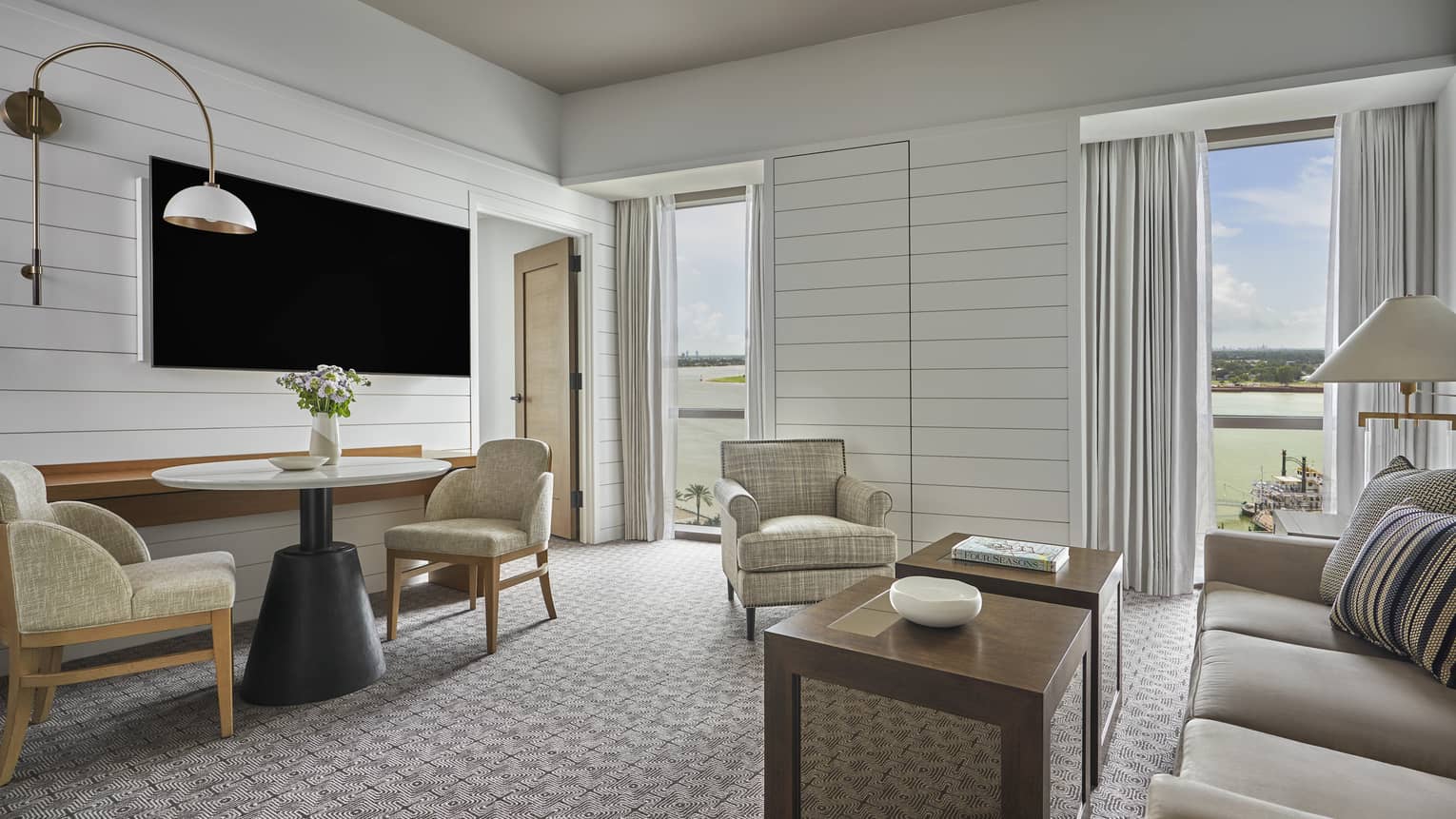 Luxury living room with grey sofa, armchair and two-seater table overlooking a river