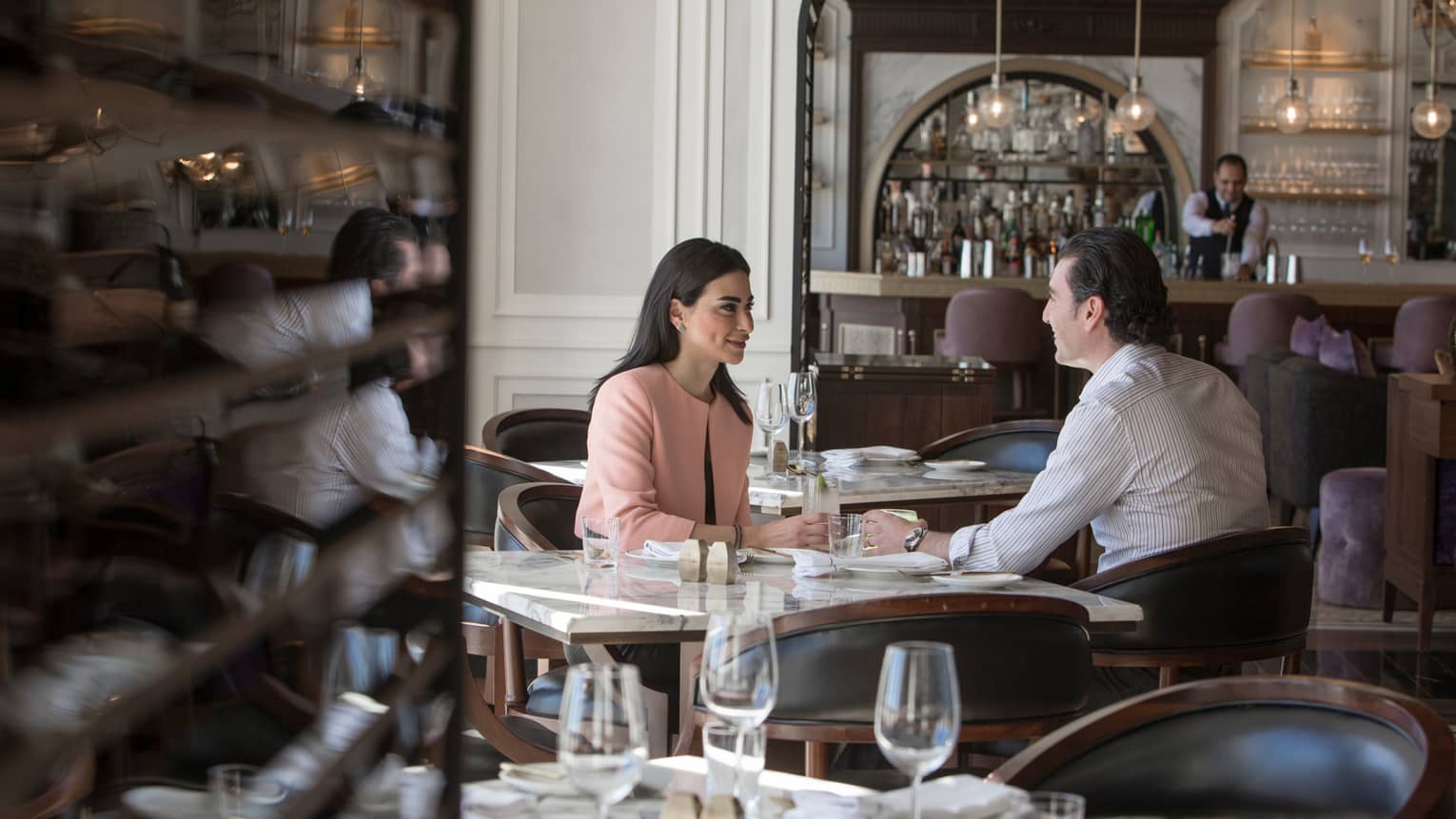 Couple dine at table in La Capitale restaurant, bar and bartenders in background
