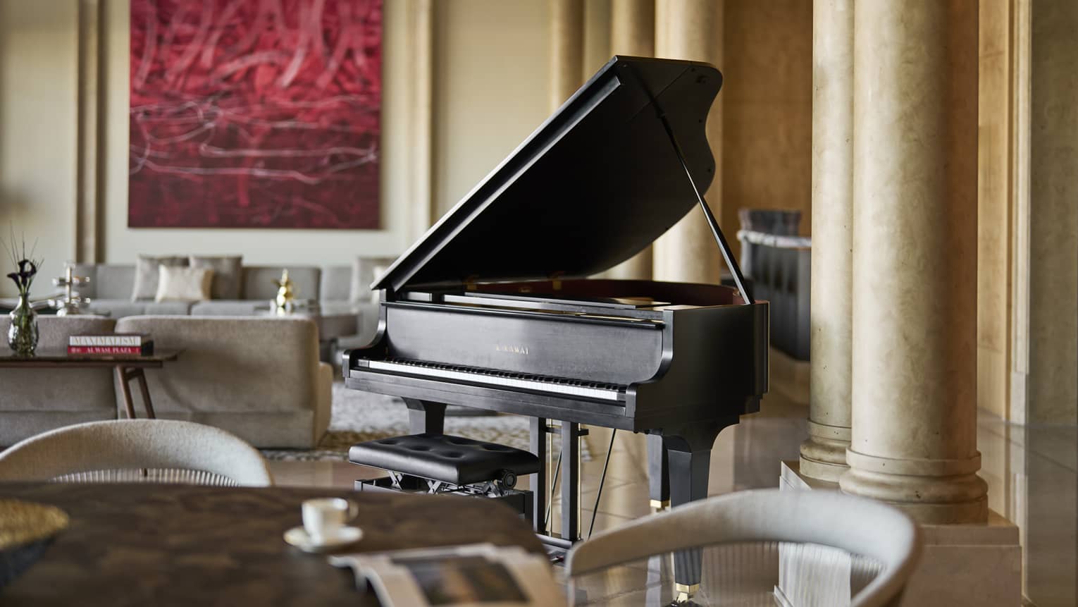 Black baby grand piano sits in the middle of a large hotel suite's living room