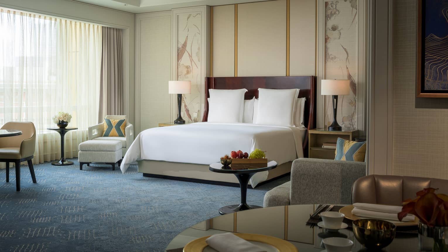 Premier Room hotel bed with white linens against wall with decorative panels, armchair by window