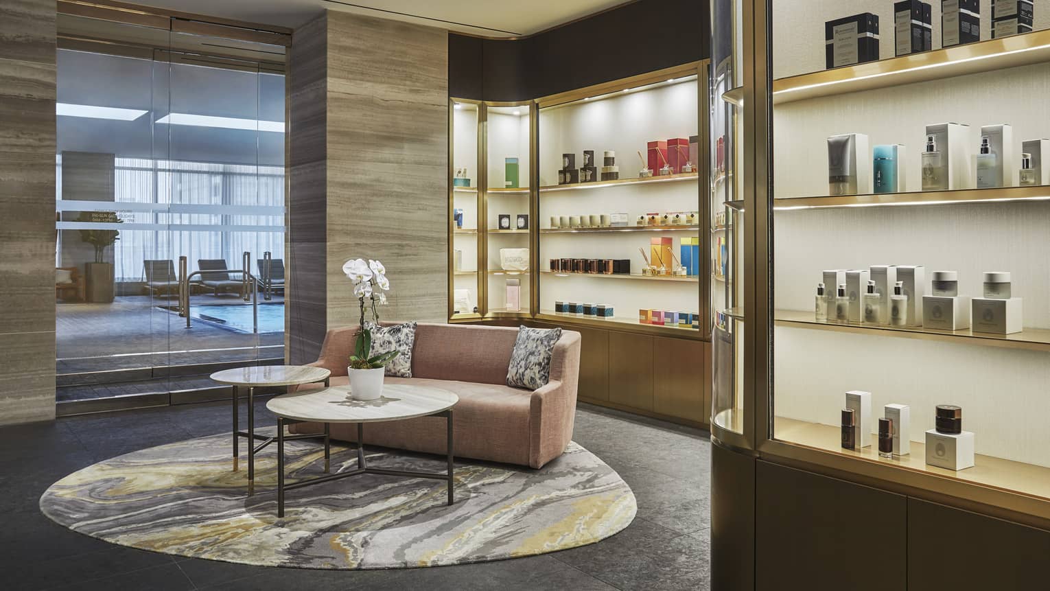 A pink loveseat sits in the centre of the lobby surrounded by illuminated products in showcases. 