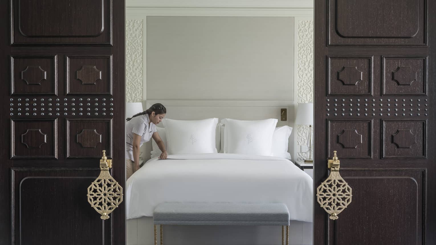 Housekeeping staff member makes bed in the Ambassador Suite
