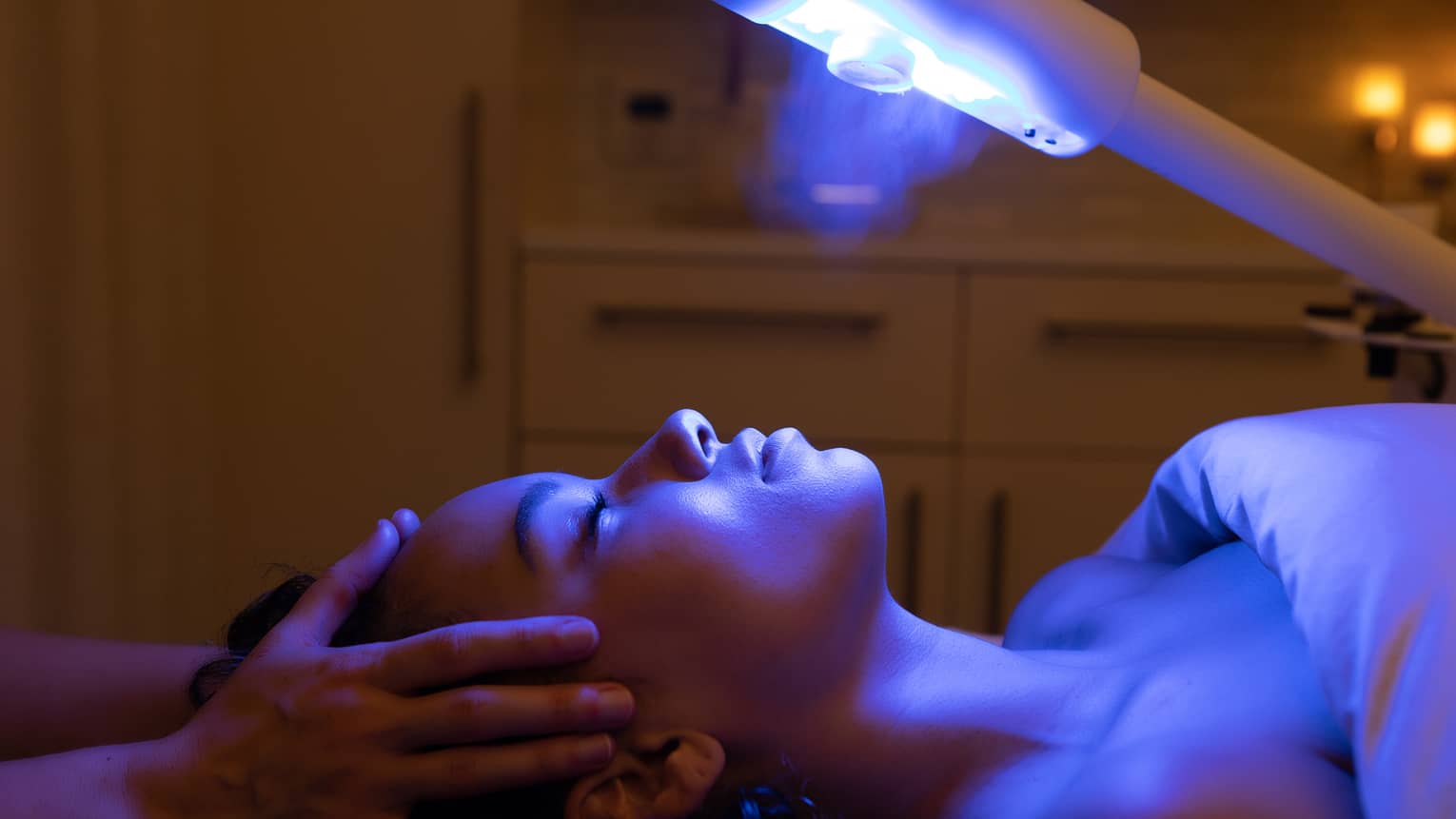 A guest laying on a spa table and receiving a light therapy treatment 