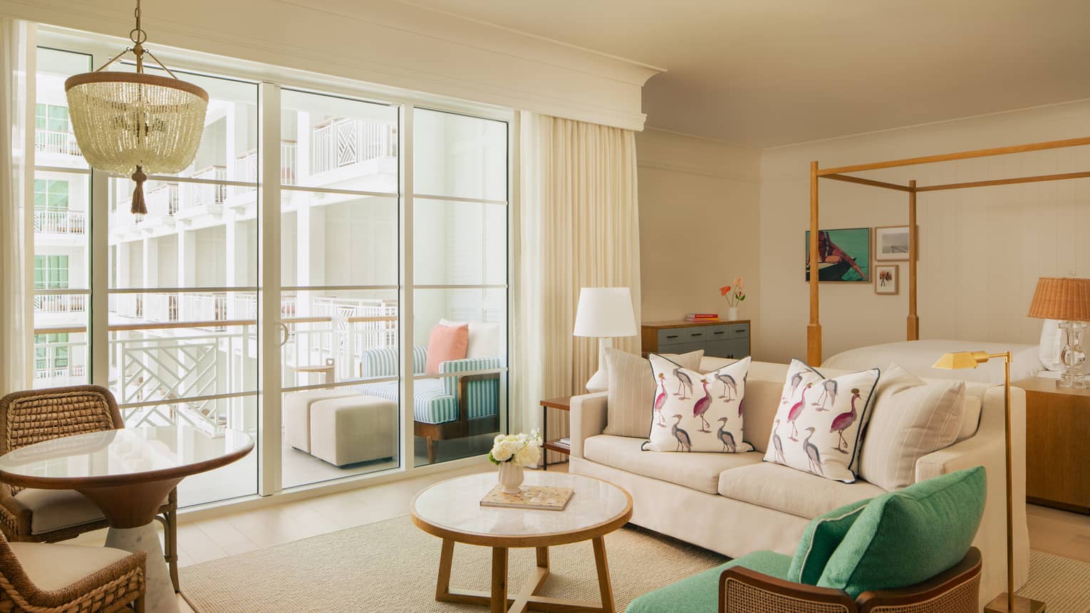 Hotel studio suite with four-post bed, sofa, arm chair and walk-out balcony