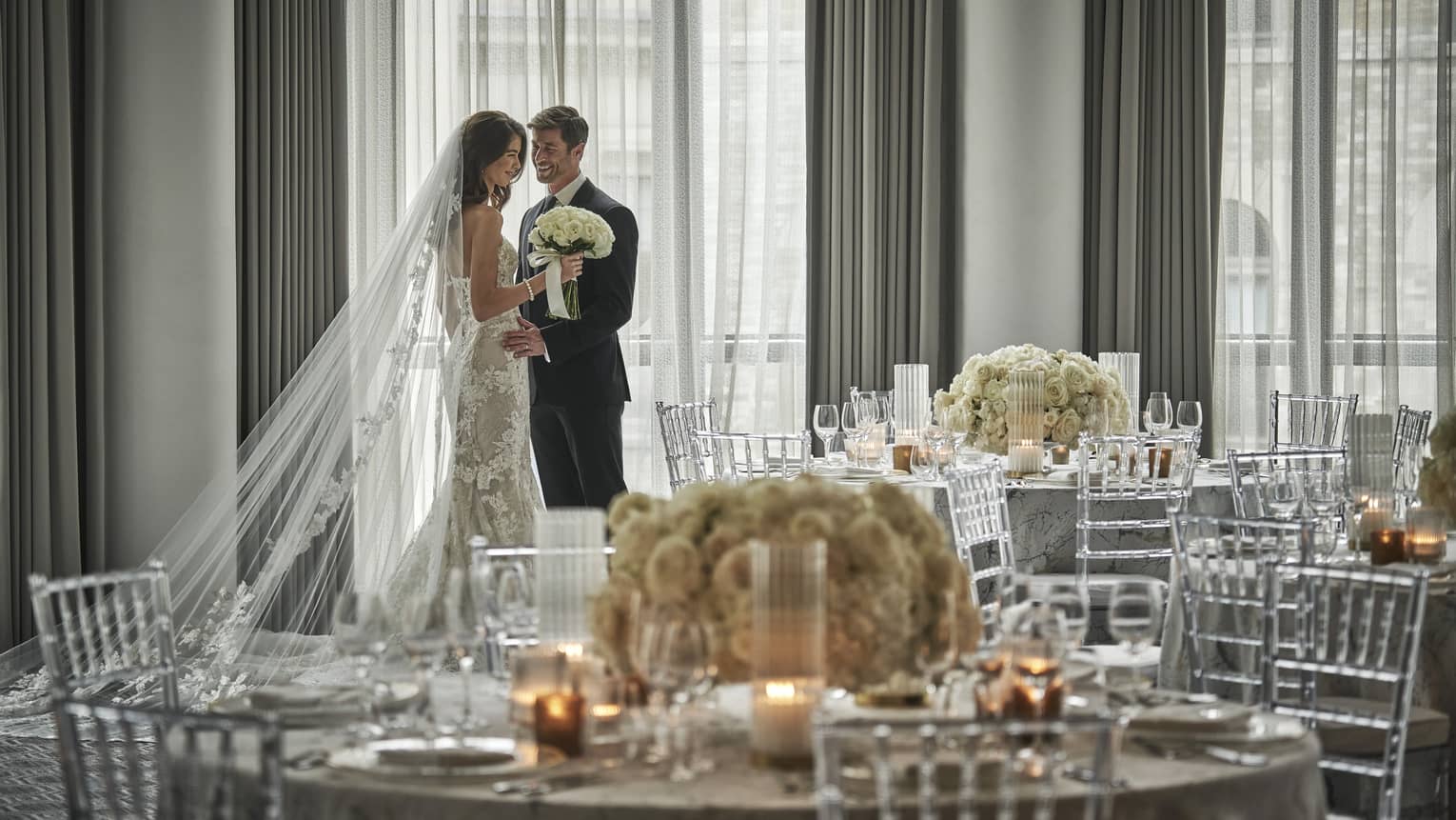 Bride and groom behind large round wedding banquet table with glowing candles