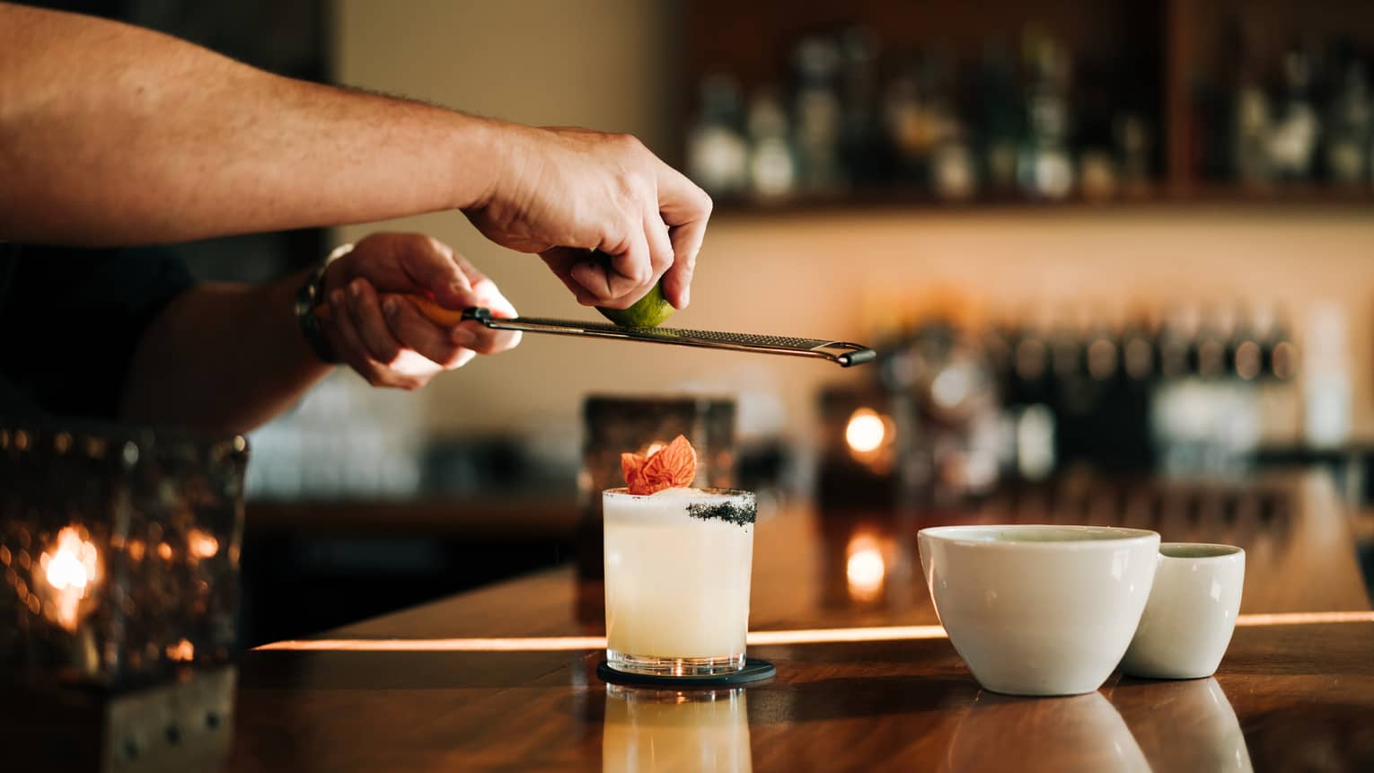 A person standing at a bar and making a drink in a glass