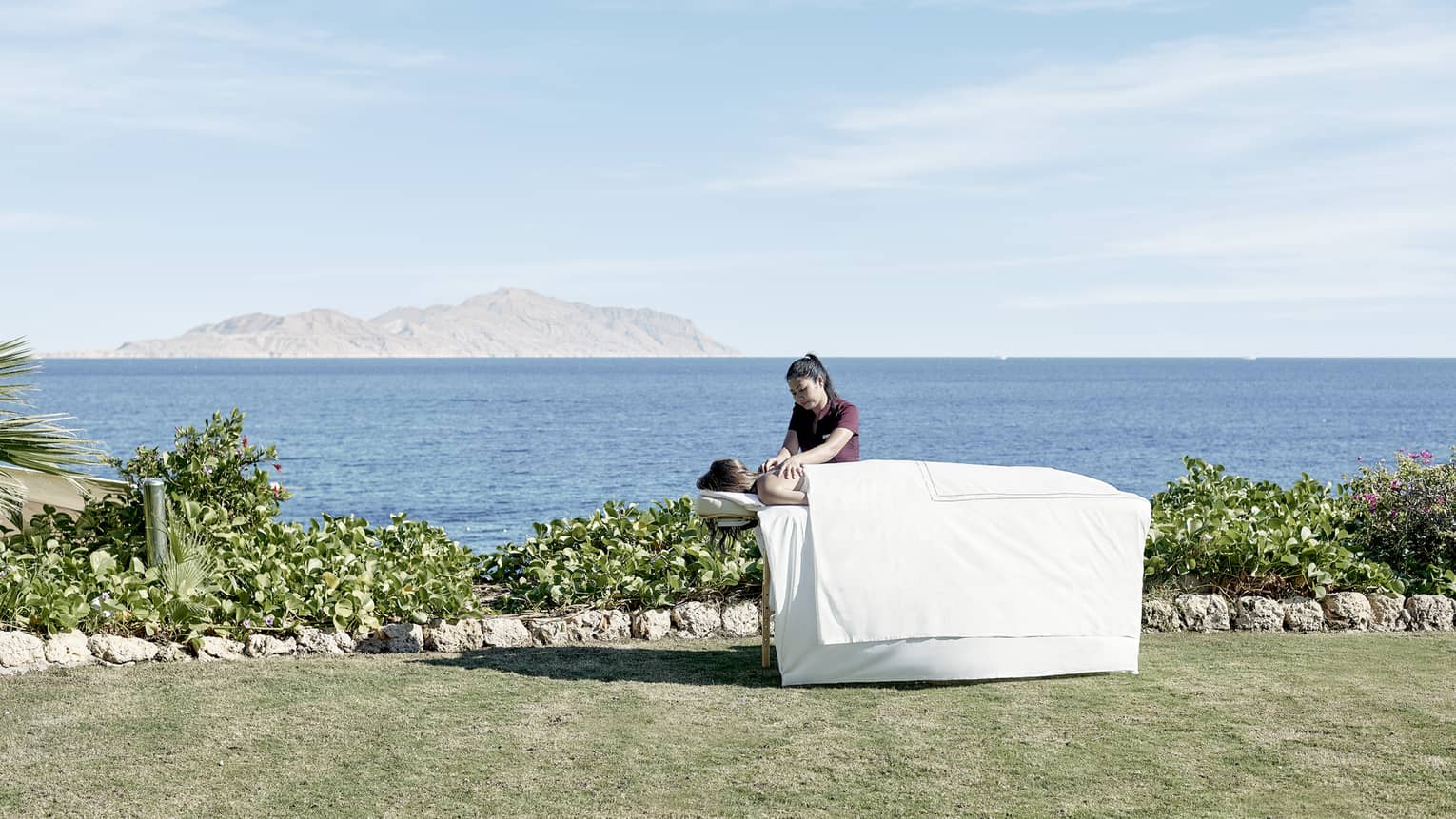 Massage therapist during an outdoor session with blue skies and views of the Red Sea