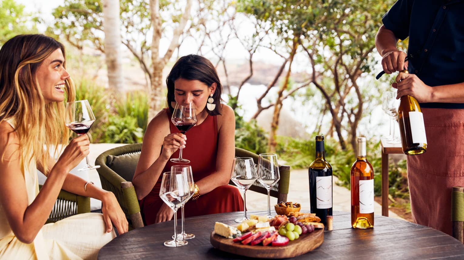 Two women drinking wine outside.