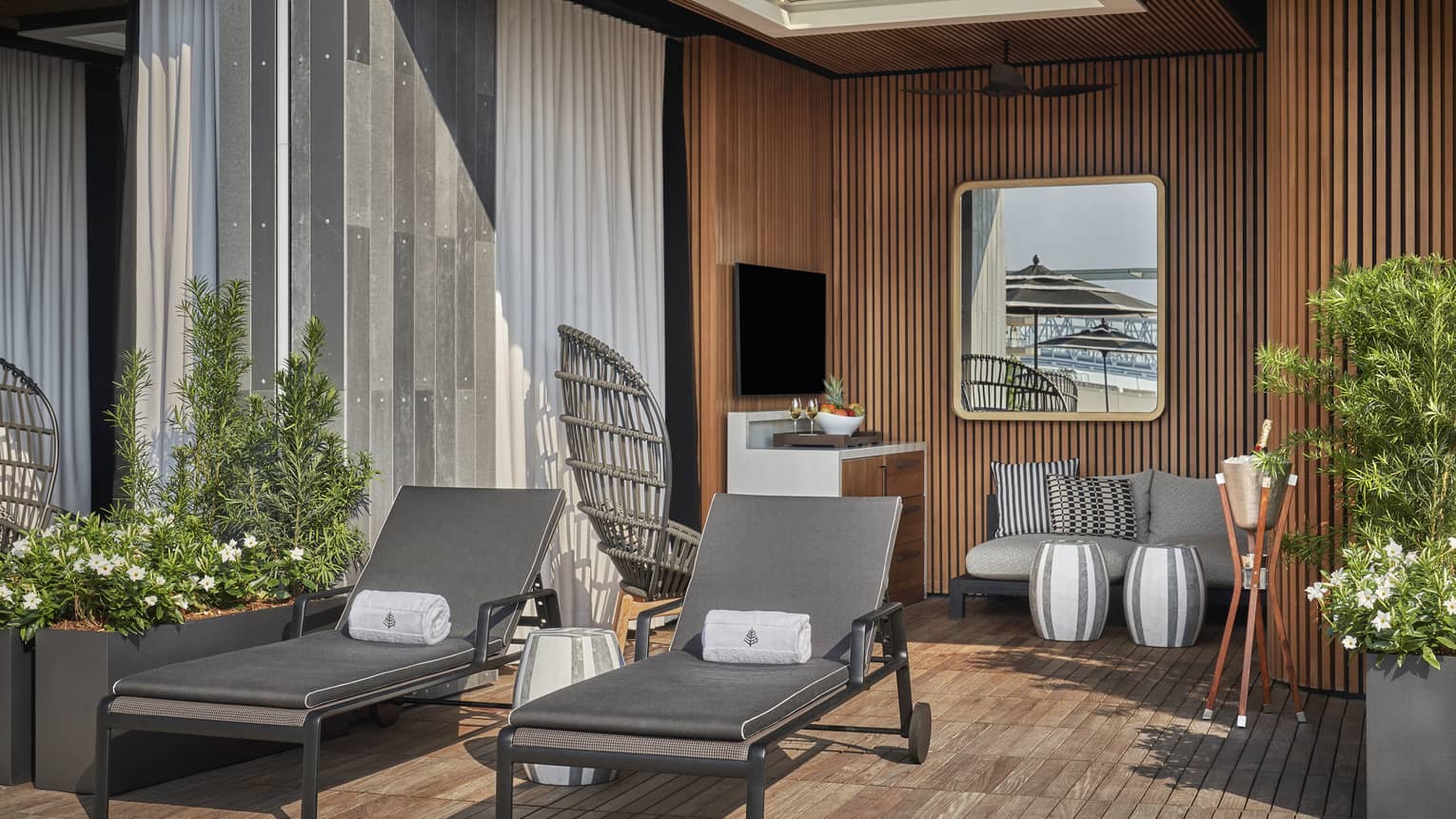A cabana with two lounge chairs a sofa and plants.