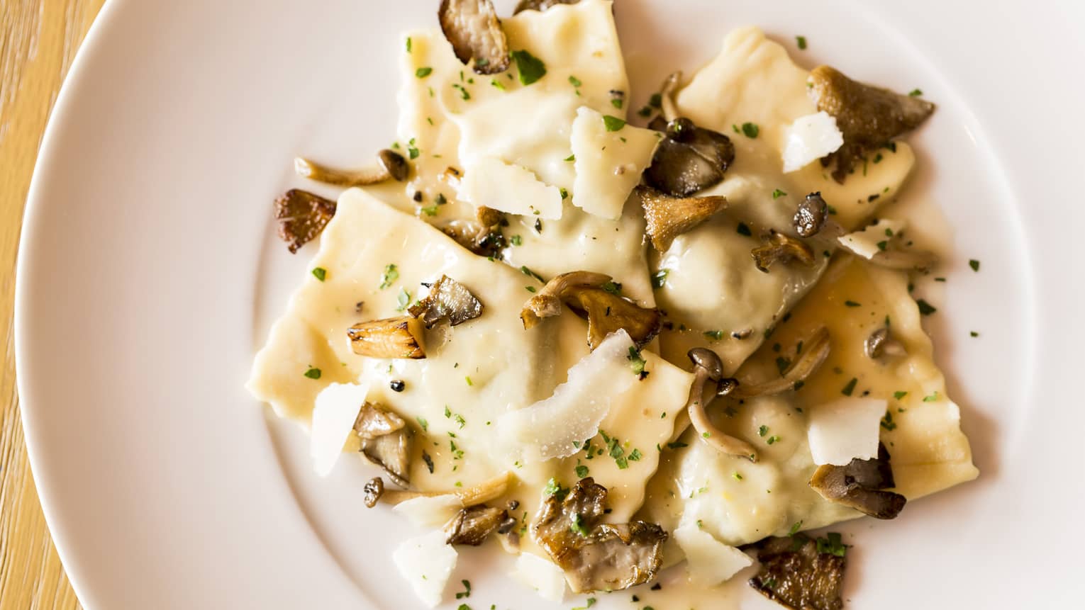 Veal Ravioli pasta garnished with shaved parmesan cheese, mushrooms on plate
