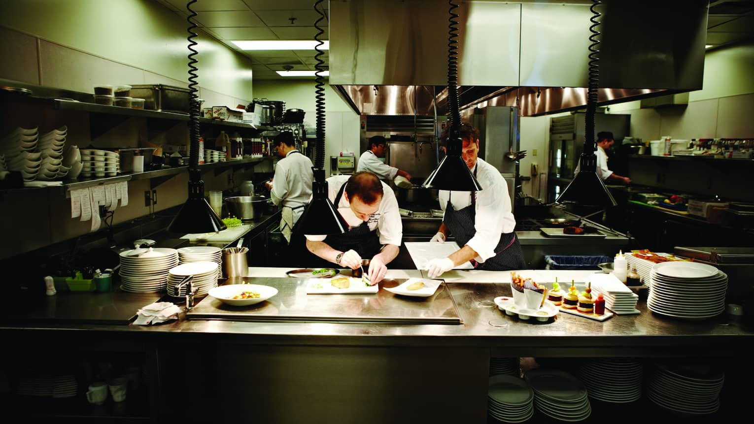 Chefs at work plating gourmet meals in stainless-steel Goldfinch Tavern kitchen