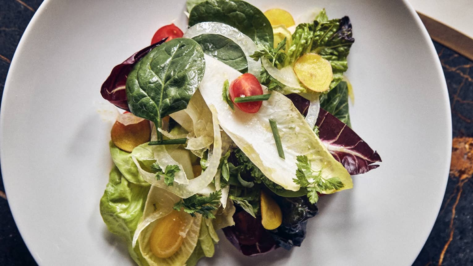 A salad with greens and tomatoes.