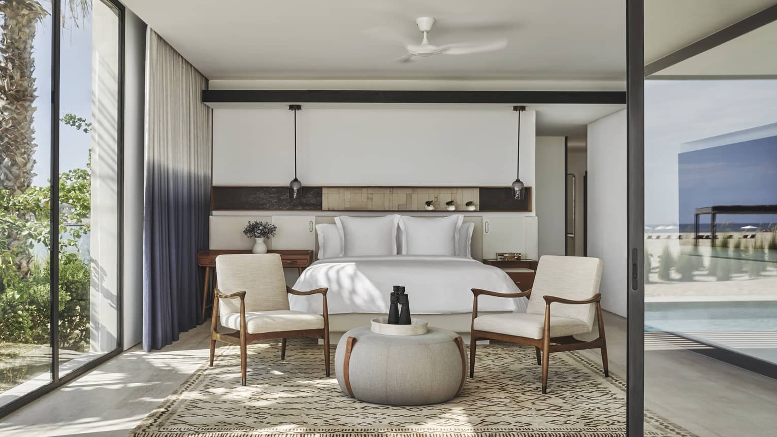 Two Bedroom Sunrise Suite bedroom with King bed, white linens, twin arm chairs, floor-to-ceiling windows with two-tone curtains