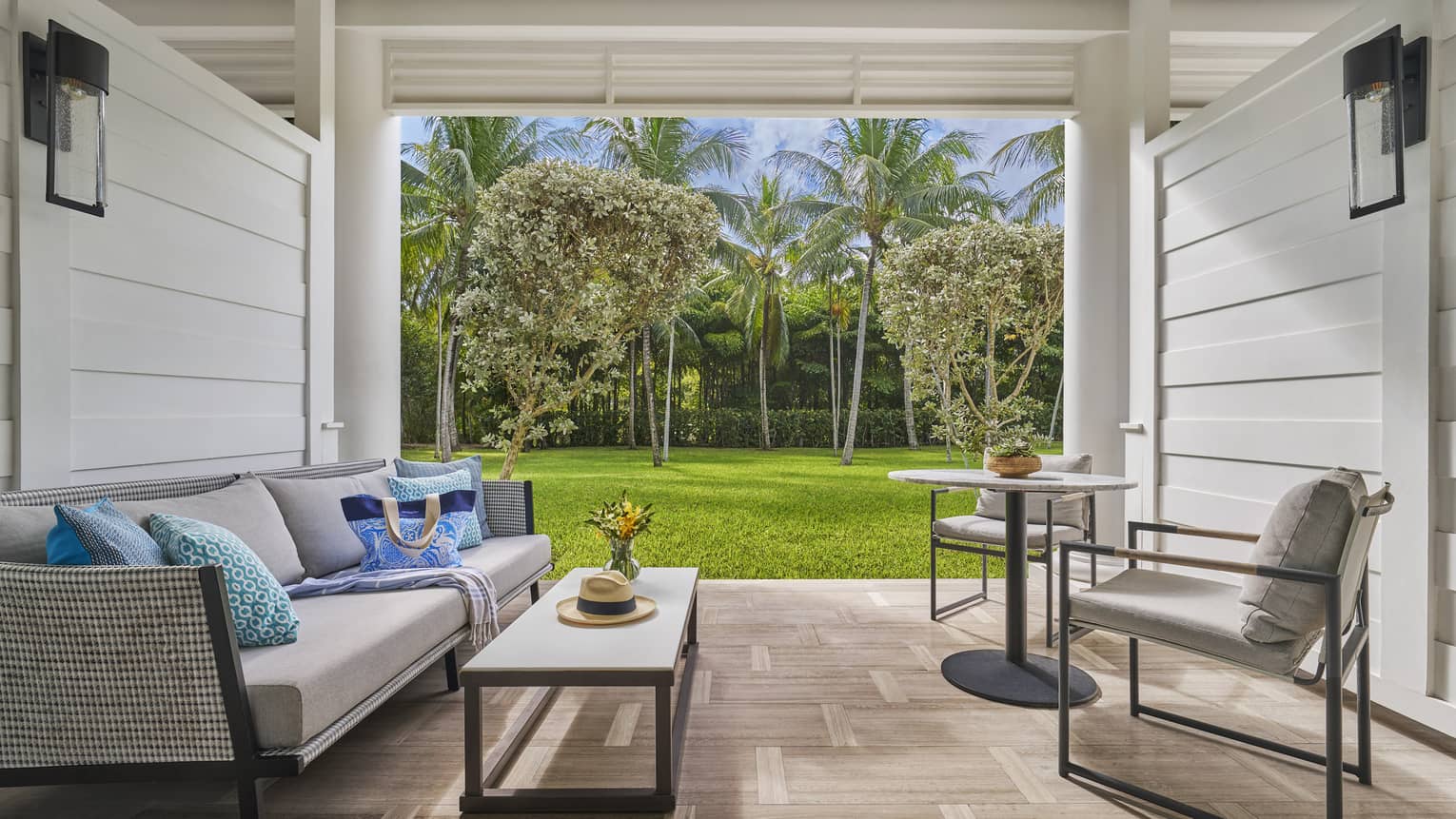 Private patio with sofa, two coffee tables and two chairs, looking out to garden
