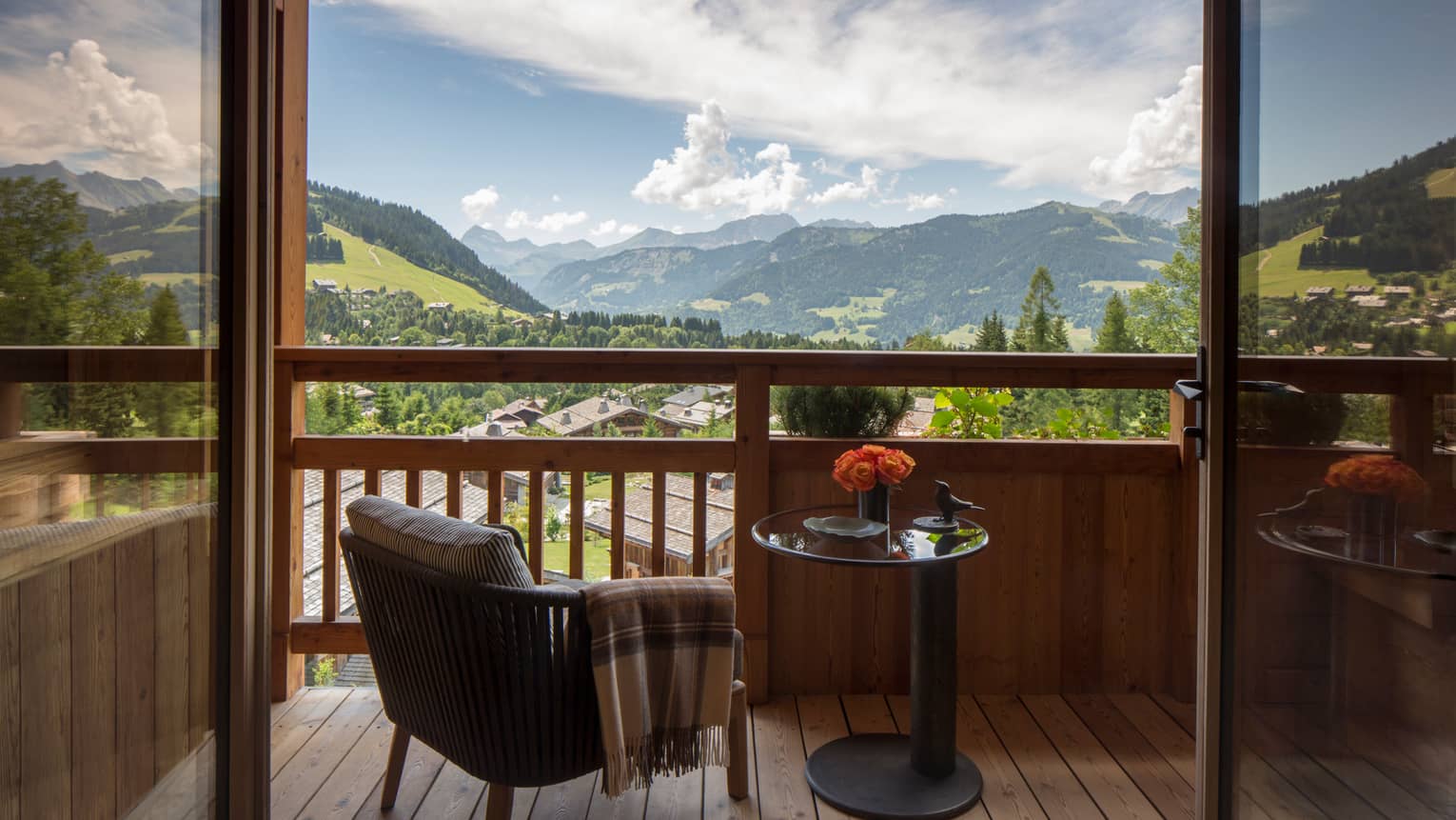 Suites des Alpes patio chair with blanket, table with flowers on balcony overlooking French Alps
