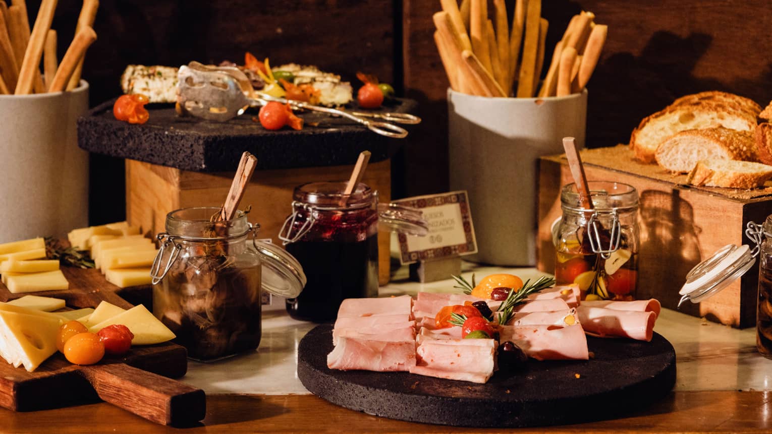 A display of sliced cheeses, meats and bread along with condiments