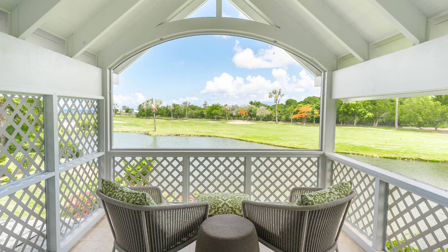 Covered terrace with two chairs and side table, overlooking pond and golf course
