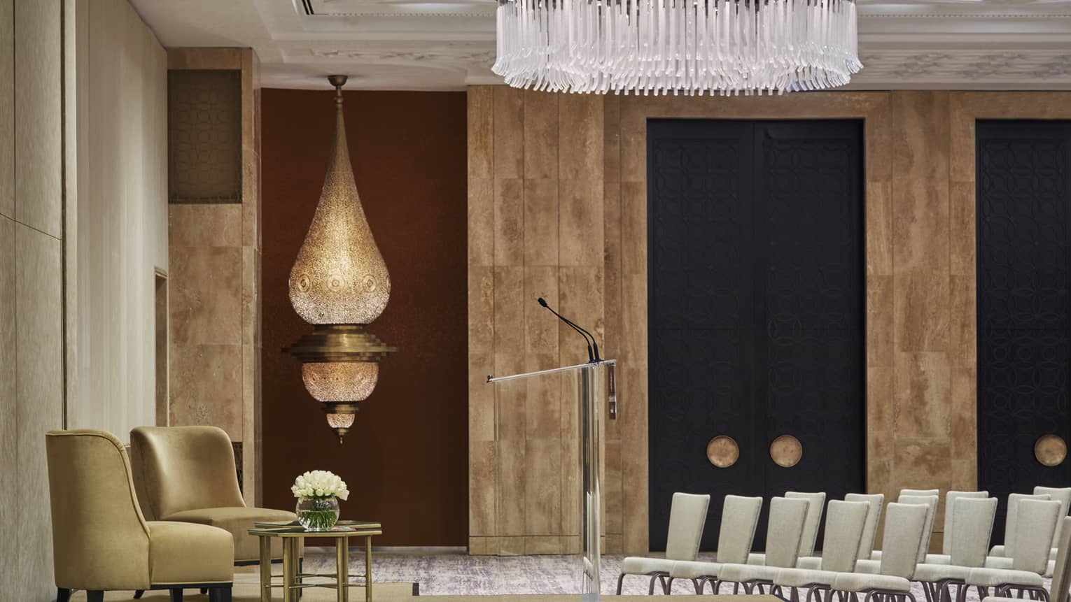 Ballroom with rows of chairs in conference set up, two velvet armchairs on podium, large Moroccan lamp