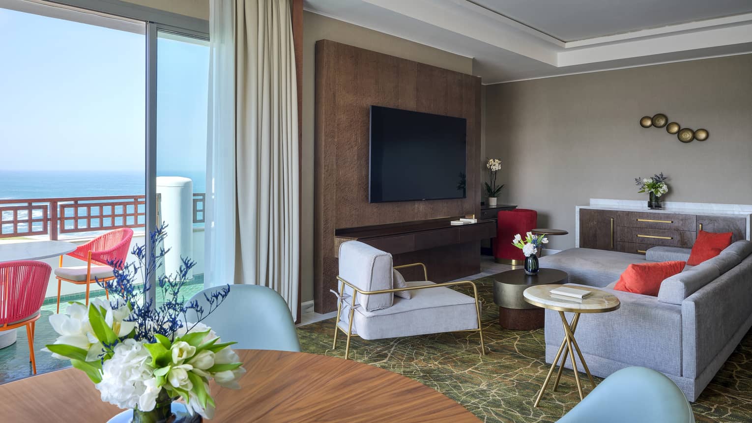 One-bedroom suite at Four Seasons Hotel Rabat, featuring a round dining table and turquoise chairs, a sea-view balcony and a living room