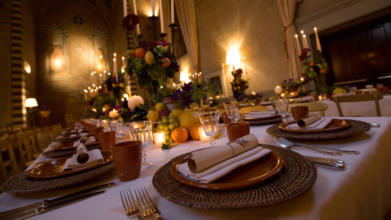 Close-up of plates, place settings on dining table with fruit, candles 