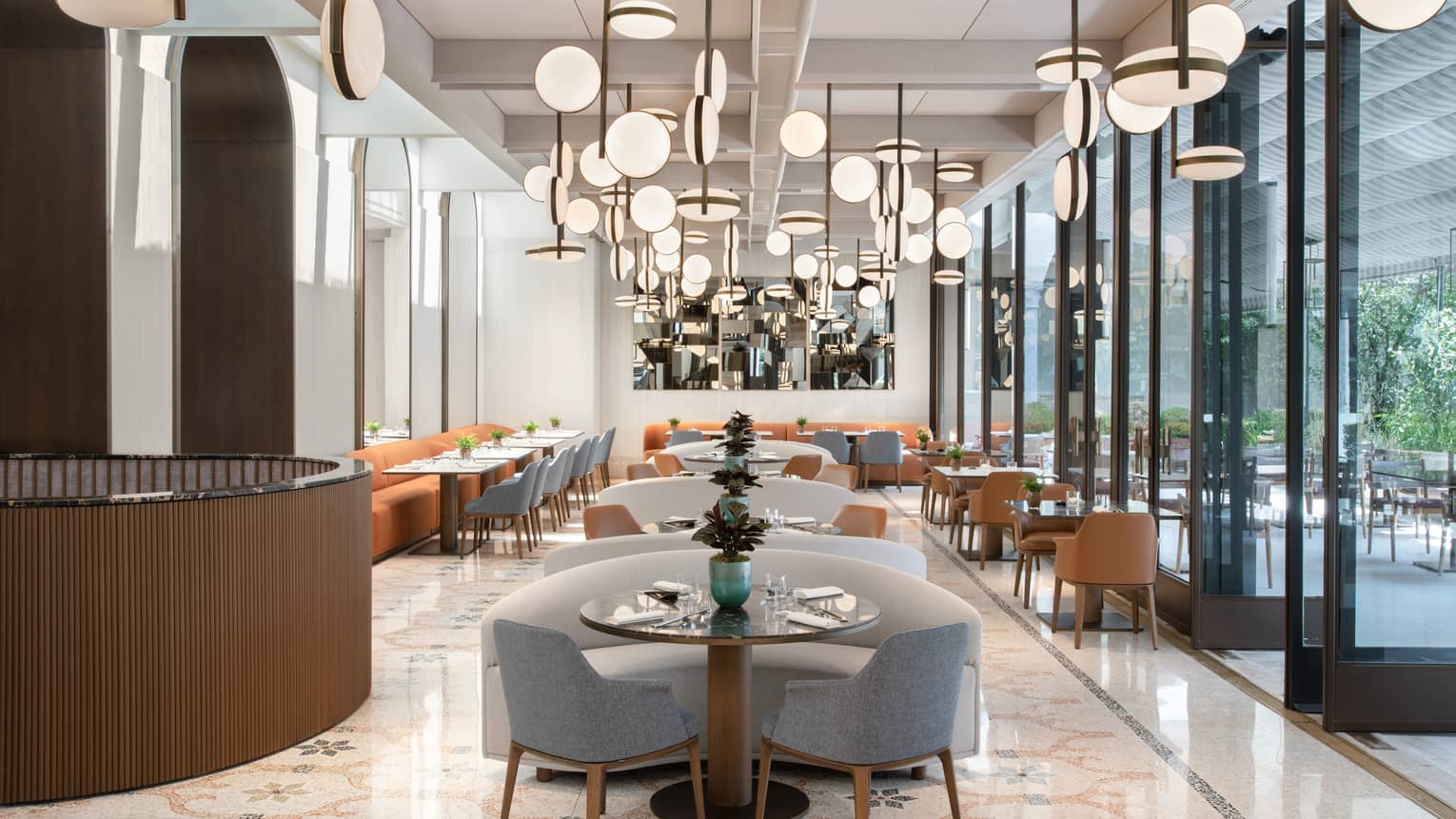 A cleanly decorated dining room with an array of unique lighting fixtures above