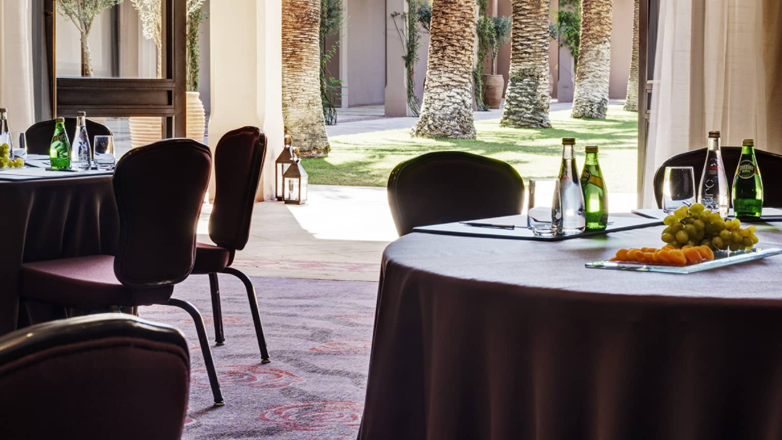 View past small round banquet tables to open wall leading to sunny patio