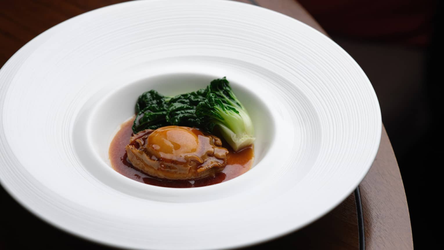 Abalone and vegetable in a white bowl.