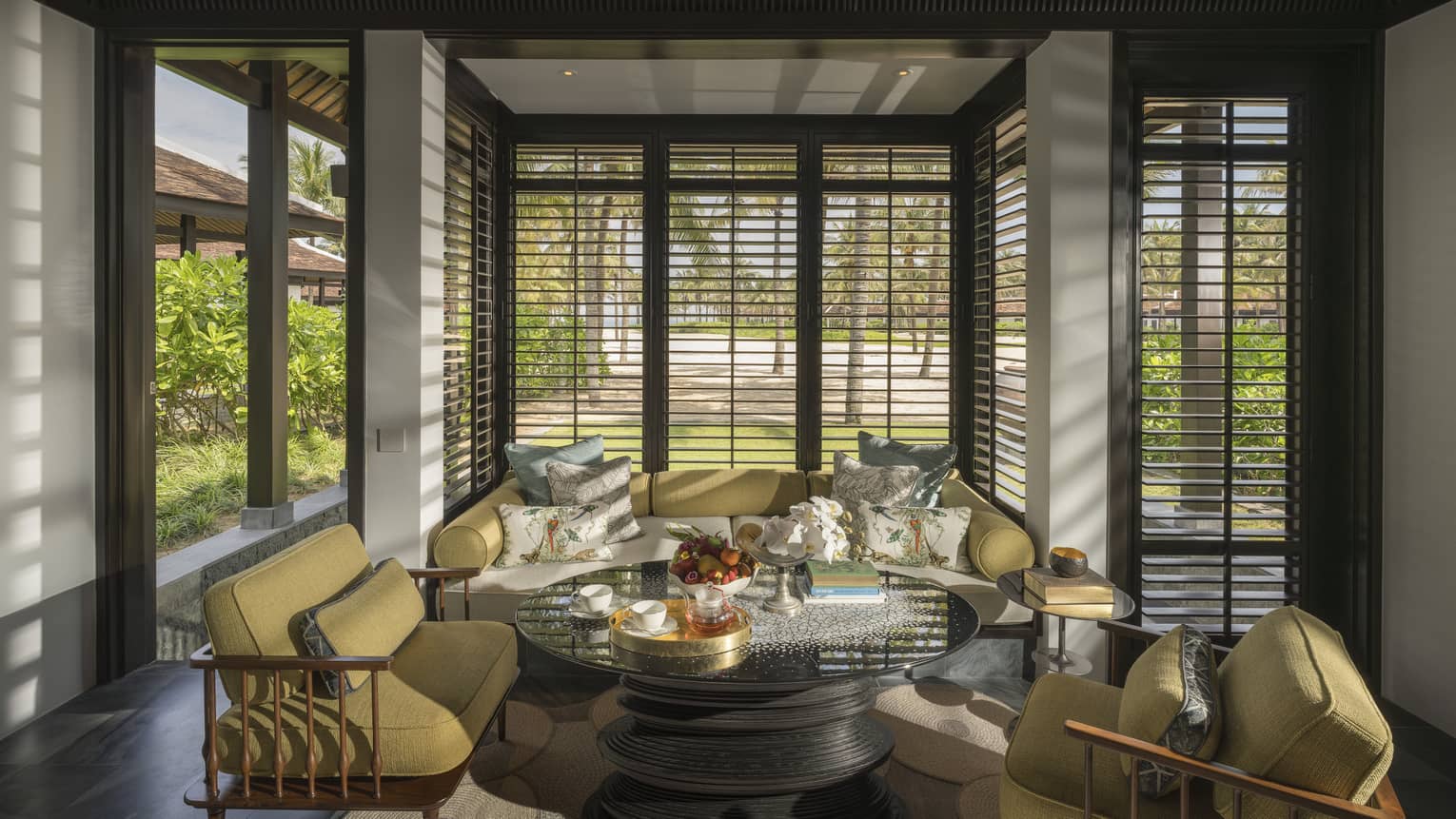 Guest room living area with mustard-coloured armchairs and sofa with floor-to-ceiling windows with. beach views